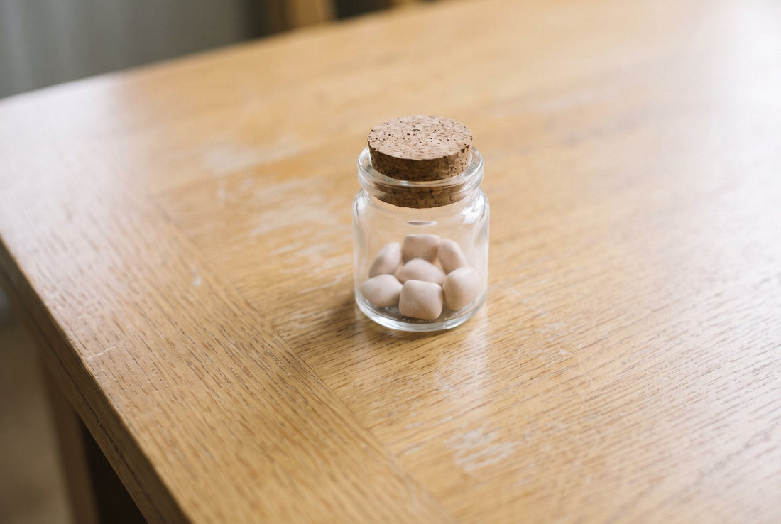 Gum pellets in a plain glass jar with a cork lid on an oak table
