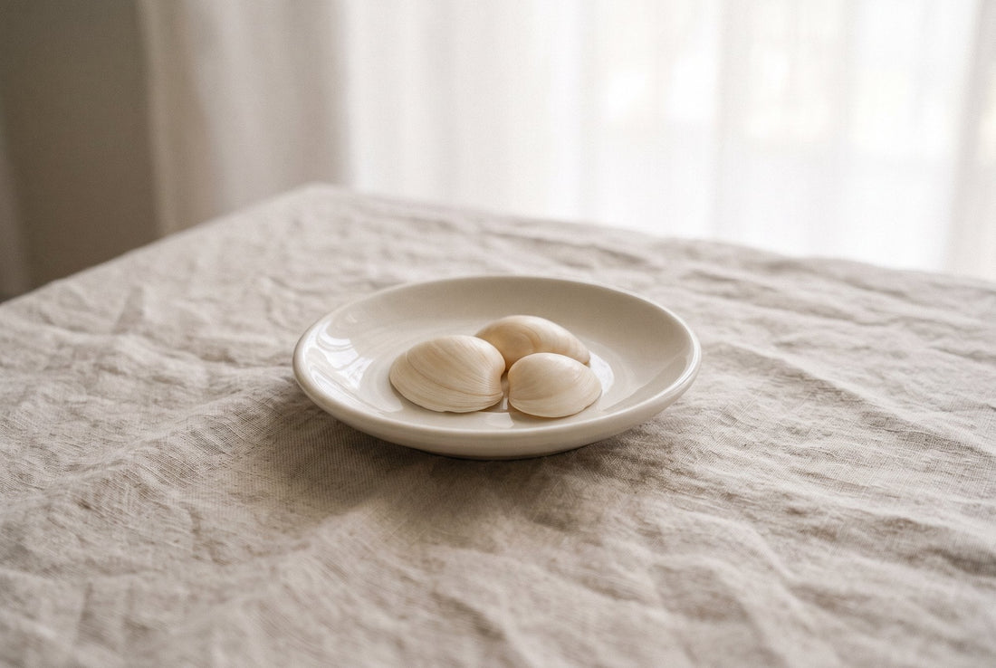 Weiße Muscheln in einer kleinen Keramikschale auf Leinen